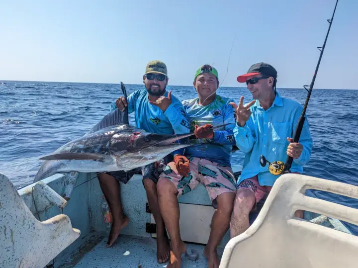Guests holding a marlin on a fishing tour in Puerto Escondido